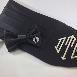 May include: Black satin bow tie and cummerbund set with a white monogrammed initial "JTG" on the cummerbund.