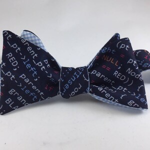 May include: A blue bow tie with a white and blue checkered pattern on the back. The front of the bow tie features code printed in blue, red, and pink.
