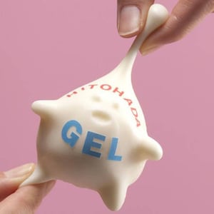 K&ouml;nnte beinhalten: Wei&szlig;es gelartiges Spielzeug mit der Aufschrift "HITO HADA GEL". Das Spielzeug wird von einer Hand gedehnt und gezogen.