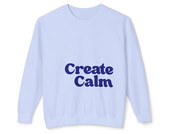 May include: A light blue crewneck sweatshirt featuring the text "Create Calm" printed in a bold, dark blue, rounded font across the center of the chest. The garment has long sleeves, a ribbed neckline, and ribbed cuffs at the wrists and waist.