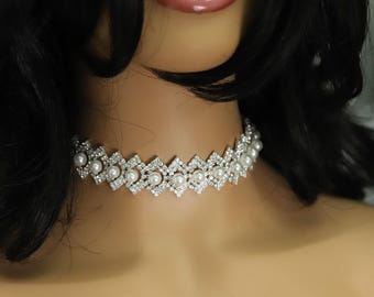 May include: A silver choker necklace with a geometric design featuring alternating clear rhinestones and white pearls.