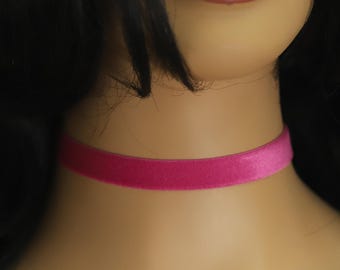 May include: A close-up of a vibrant pink velvet choker necklace. The choker is a simple band of soft, plush material, encircling the neck. The color is a bright, saturated pink, adding a pop of color.