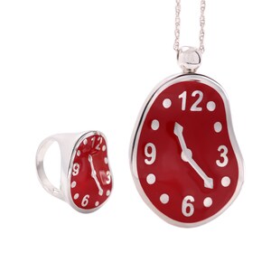 May include: A silver necklace with a red melted clock pendant and a matching silver ring with a red melted clock. The clock face has black numbers and hands.