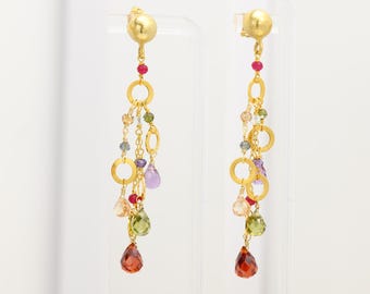 May include: Gold dangle earrings with a cluster of colorful gemstones, including red, green, purple, and orange. The earrings feature multiple gold circles and chains.