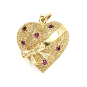 May include: A gold heart-shaped pendant with a bow and pink gemstones. The pendant is textured and has a gold ribbon around it.