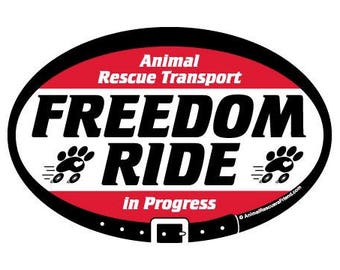 May include: Oval sticker with a black border, featuring the words "FREEDOM RIDE" in bold black letters. The sticker also includes the text "Animal Rescue Transport" and "in Progress" in red. Paw prints and a belt design are also included.