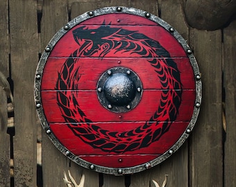 May include: A round wooden shield with a red background and a black dragon design. The shield has a metal rim with studs and a metal center boss.