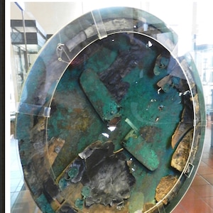 May include: A close-up view of the inside of an Etruscan shield. The shield is made of bronze and is decorated with a geometric pattern. The shield is in a museum display case.