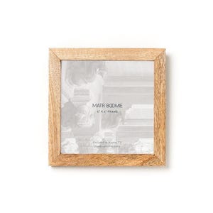 May include: A square wooden picture frame with a light brown natural grain finish. The frame contains a display insert with the text MATR BOOMIE 15.24 CM X 15.24 CM FRAME, Designed in Austin, TX, Handcrafted in India printed in black on a white background.