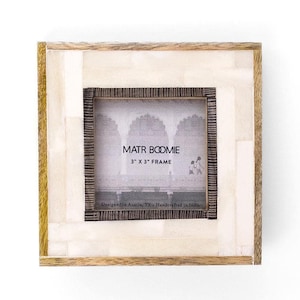 May include: A square picture frame featuring a light-colored, rectangular-tiled inlay border surrounded by a natural wood edge. The center display area contains text reading MATR BOOMIE 3" X 3" FRAME and Designed in Austin, TX. Handcrafted in India.