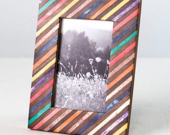 May include: A rectangular picture frame featuring a diagonal striped pattern of dark brown wood slats interspersed with vibrant, multi-colored resin strips in shades of teal, pink, orange, yellow, purple, and blue, holding a black and white photo.