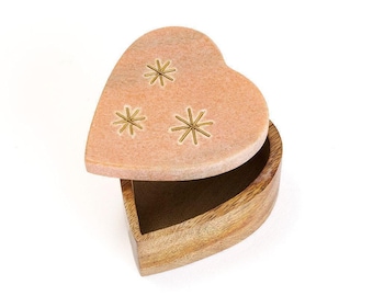 May include: A heart-shaped box with a light pink stone lid featuring three engraved gold-colored starburst designs. The base of the box is crafted from natural brown wood, showing a visible grain pattern, and the lid is slightly ajar.
