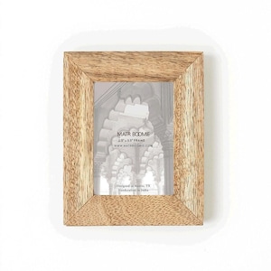 May include: A rectangular picture frame made of light brown wood with a visible grain pattern. The frame holds a display card with the text MATR BOOMIE, 2.5 x 3.5 FRAME, WWW.MATRBOOMIE.COM, Designed in Austin, TX, and Handcrafted in India.
