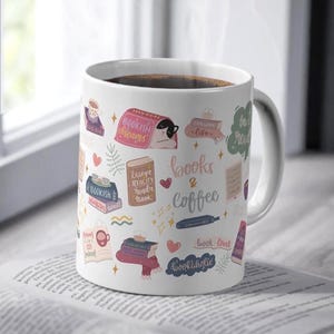 Pode incluir: Caneca de cerâmica branca com um design colorido de livros, café e um gato. A caneca tem o texto "books & coffee".
