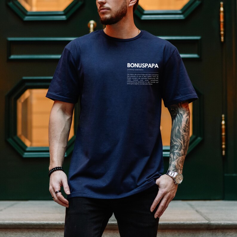 May include: A navy blue t-shirt with the text "BONUSPAPA" and a definition of the word in white print.
