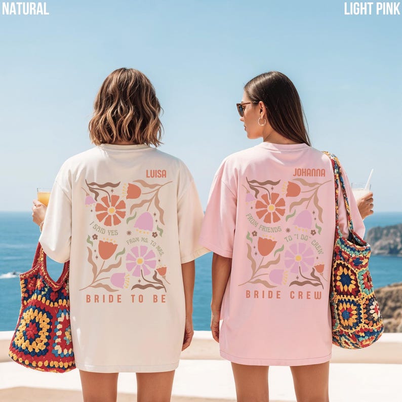 May include: Two oversized t-shirts, one natural and one light pink, with floral designs and text. The natural shirt says "Bride to Be" and "Luisa." The pink shirt says "Bride Crew" and "Johanna."
