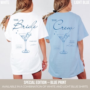May include: A white t-shirt with blue text reading The Bride, I Said Yes!, August 2026, and a martini glass graphic, alongside a light blue t-shirt with blue text reading The Crew, We Say Cheers!, August 2026, and a martini glass graphic.