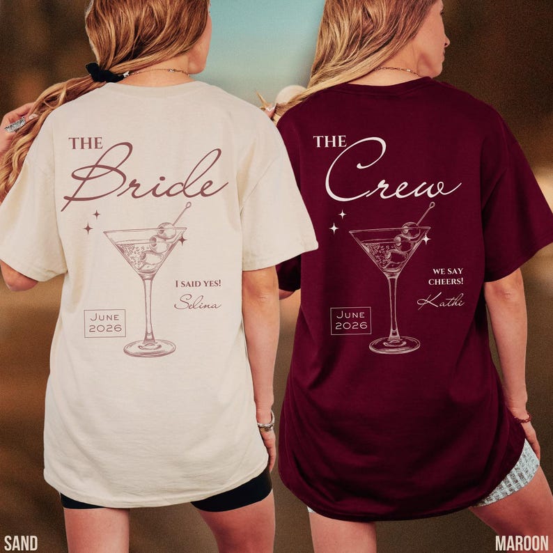 May include: A sand-colored t-shirt with 'THE Bride', 'I SAID YES!', 'Selina', and 'JUNE 2026' text and a martini glass graphic, and a maroon t-shirt with 'THE Crew', 'WE SAY CHEERS!', 'Kathi', and 'JUNE 2026' text and a martini glass graphic.