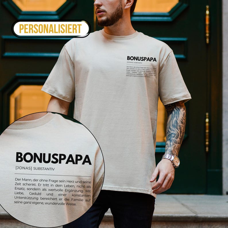 May include: A beige t-shirt with the text "BONUSPAPA [JONAS] SUBSTANTIV" and a definition of the word. The text is in black and the shirt is worn by a person with tattoos on their arm.