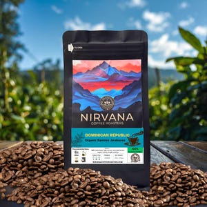 May include: A black bag of Nirvana Coffee Roasters Dominican Republic coffee beans. The bag features a mountain landscape design in blue, red, and orange. Coffee beans are scattered around the bag on a wooden surface.
