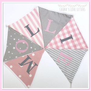 May include: A pink and gray fabric banner with the word "LOVE" spelled out in large, gray letters. The banner is made of different patterned fabrics, including stripes, polka dots, and stars.