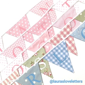 May include: A pink and blue fabric banner with the letters "ATOR" in pink and "OR" in blue. The banner is made of different patterned fabrics, including gingham, polka dots, and floral prints. The banner is decorated with white stars and zigzags. The text "@laurasloveletters" is visible at the bottom of the image.