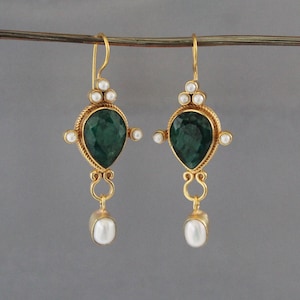 May include: A pair of gold drop earrings featuring a central pear-shaped faceted dark green gemstone, accented with small white pearls arranged in clusters at the top and sides, and a single oval white pearl dangling from a curved gold link.
