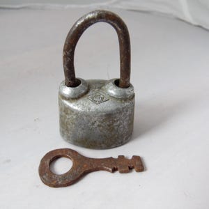 May include: A vintage silver padlock with a rusty key. The padlock has a diamond-shaped logo with the text "WEST" inside.