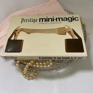 May include: A vintage box of "Prestige mini-magic" stretch non-run hosiery. The box features an illustration of a leg being stretched. The text on the box reads "It stretches to any length to fit you!" The box is resting on a glass dish with a pearl necklace.