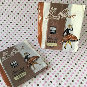 May include: Two vintage packages of Bond Street Bareleg Nylons. The packaging is brown, white, and orange with a retro illustration of a woman in a dress. The text on the packaging includes "Bond Street," "Nylon," and "Mesh."