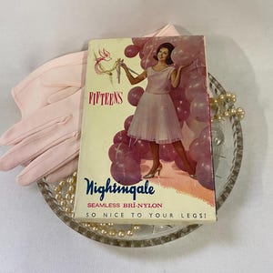 May include: A vintage advertisement for "Nightingale" seamless Bri-Nylon stockings. The cover art features a woman in a pink dress holding balloons. The image includes a pair of pink gloves, a glass dish, and a strand of pearls.