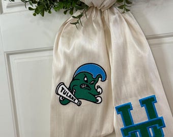 May include: A white graduation sash with a green and blue Tulane University mascot and the letters "TU" in green and blue.