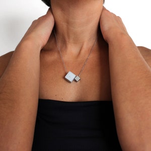 Geometric necklace with silver chain made of concrete & stainless steel cubes, from the architectural concrete jewelry collection ORTOGONALE