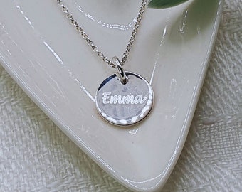 Może przedstawiać: Srebrny naszyjnik z okrągłym wisiorkiem, na którym napisano "Emma".