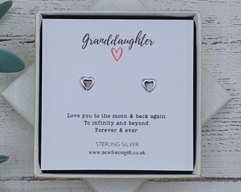 Może przedstawiać: Białe pudełko prezentowe z zestawem srebrnych kolczyków w kształcie serca. Pudełko zawiera napis "Granddaughter" z różowym sercem i tekst "Love you to the moon & back again. To infinity and beyond. Forever & ever. Sterling Silver www.newforestgift.co.uk"