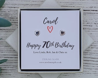 Może przedstawiać: Białe pudełko prezentowe z kartką w środku, na której napisano "Carol Szczęśliwego 70. urodzin Love Linda, Rob, Jan & Chris xx Srebro Sterling www.newforestgift.co.uk" z dwoma srebrnymi kolczykami w kształcie serca.