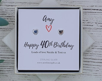Może przedstawiać: Białe pudełko prezentowe z kartką w środku, na której napisano "Amy" z czerwonym sercem, "Happy 40th Birthday", "Loads of love Natalie & Toni xx", "STERLING SILVER" i "www.newforestgift.co.uk". Pudełko zawiera parę srebrnych kolczyków w kształcie serca.
