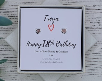 Może przedstawiać: Białe pudełko prezentowe z kartą w środku, na której napisano "Freya Happy 18th Birthday Lots of love Nanny & Grandad XXX STERLING SILVER www.newforestgift.co.uk". Karta ma czerwone serce i dwa srebrne kolczyki w kształcie serca.