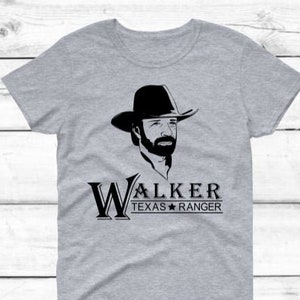 May include: A gray t-shirt with a black and white image of a man wearing a cowboy hat. The text "Walker Texas Ranger" is printed below the image.