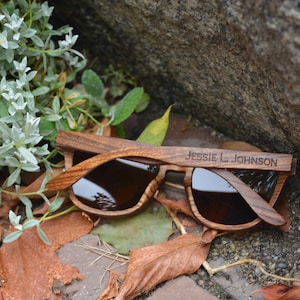 May include: Wooden sunglasses with brown lenses and the name "Jessie L. Johnson" engraved on the frame.