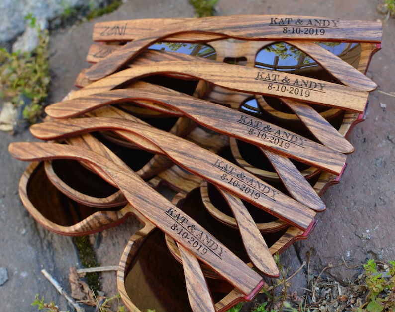 May include: A stack of wooden sunglasses with the text "KAT & ANDY 8-10-2019" engraved on each pair.