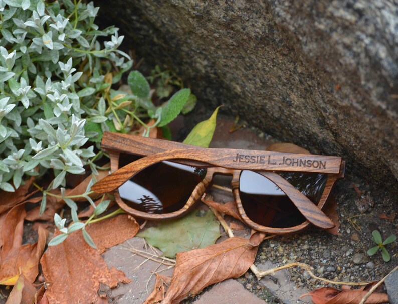 May include: Wooden sunglasses with brown lenses and the name "Jessie L. Johnson" engraved on the frame.
