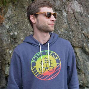 May include: A navy blue hooded sweatshirt with a colorful logo featuring a tree and glasses. The logo says "ZOM WEAR" in a circular design.