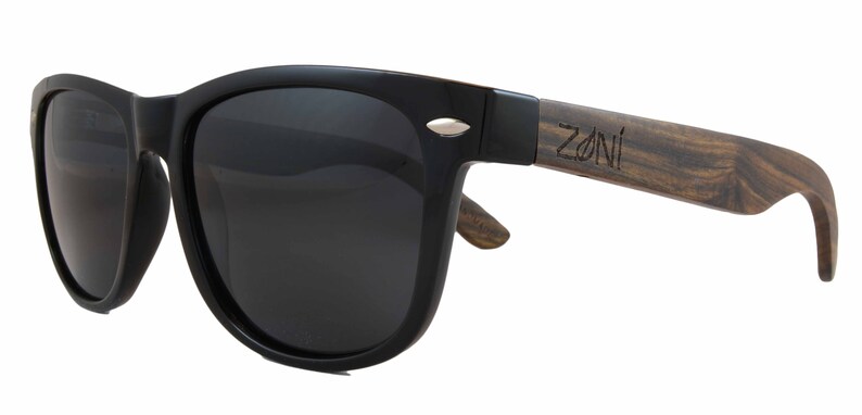 May include: Black sunglasses with a wooden frame. The frame is brown with a wood grain pattern and has the word "ZONI" engraved on it.