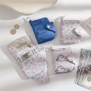 May include: Four small zippered wallets with a variety of patterns. The wallets are made of a soft fabric and have a small metal ring attached to the top. The wallets are in a variety of colors, including blue, pink, and white. The wallets have a small pocket on the outside and a larger pocket on the inside. The wallets are perfect for carrying cash, cards, and other small items.