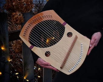 May include: A wooden lyre with a natural wood finish and a dark wood trim. The lyre has a curved shape and a sound hole in the center. The strings are strung across the top of the lyre and are held in place by tuning pegs.