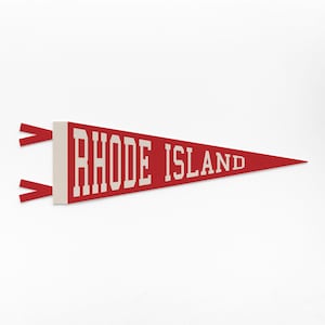 Può includere: Un gagliardetto rosso con le parole "RHODE ISLAND" in lettere bianche. Il gagliardetto ha una forma triangolare e due nastri rossi attaccati sul lato sinistro. Lo sfondo è bianco.