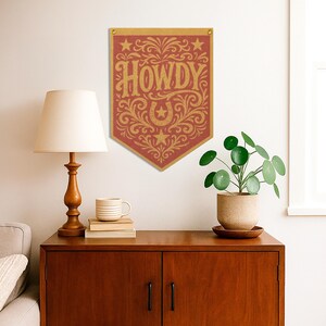a wooden cabinet with a lamp, a potted plant, and a decorative banner hanging on the wall above it.