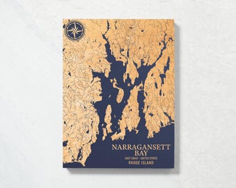 May include: A wooden map of Narragansett Bay, Rhode Island, with a compass rose in the top left corner. The map is on a blue background with the text "Narragansett Bay, East Coast - United States, Rhode Island".