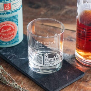 May include: A clear glass tumbler with a white silhouette of the Cincinnati skyline and the text "Cincinnati Ohio" etched on the side.